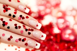 Beautiful holiday manicure with a red heart and with sparkles in the shape of a heart in my hand, and background
