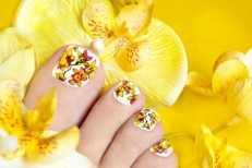 Pedicure with orchids in the women's legs on a yellow background